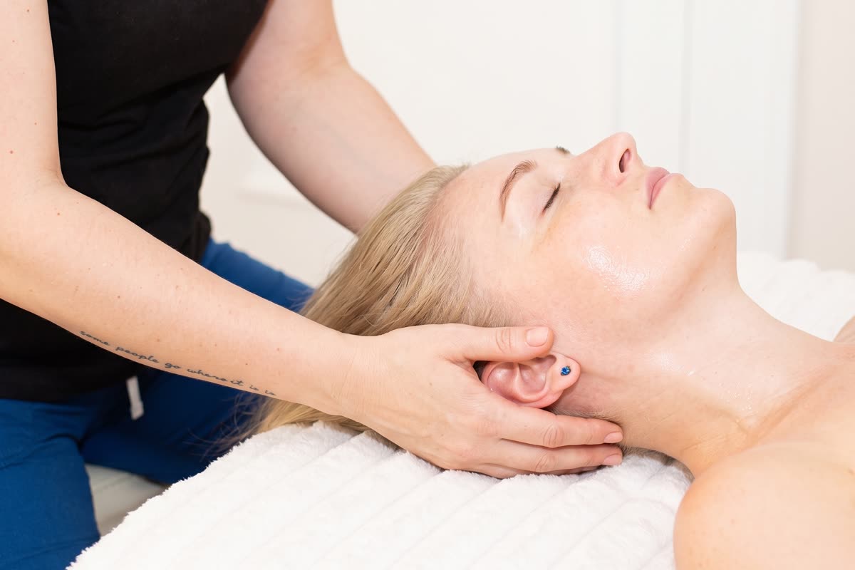 Terapeutka prowadzi głowę od podstawy czaszki podczas masażu karku i twarzy w studiu Massage 4 You
