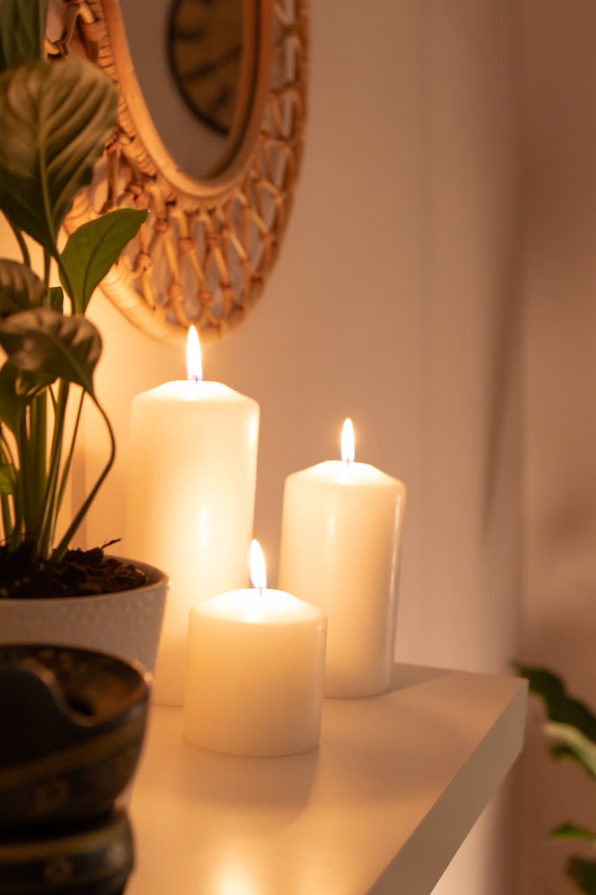 Zapalone świece i plecione lustro na półce w studiu Massage 4 You