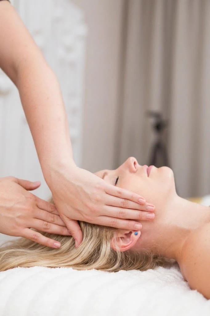 Masaż Kobido - dłonie terapeutki pracują nad twarzą i skronią klientki w studiu Massage 4 You w Poznaniu